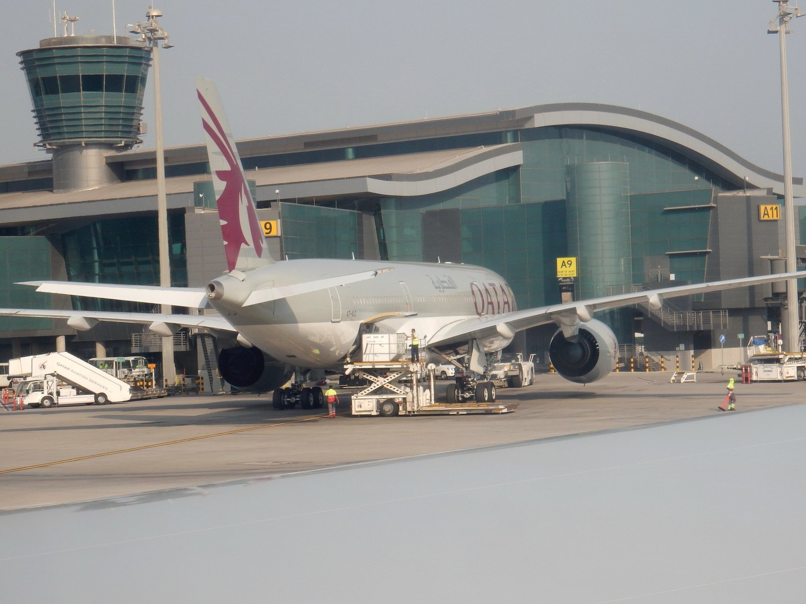 Qatar Airways Airbus A350 parked at Hamad International Airport in Doha among terminal infrastructure and other aircraft.