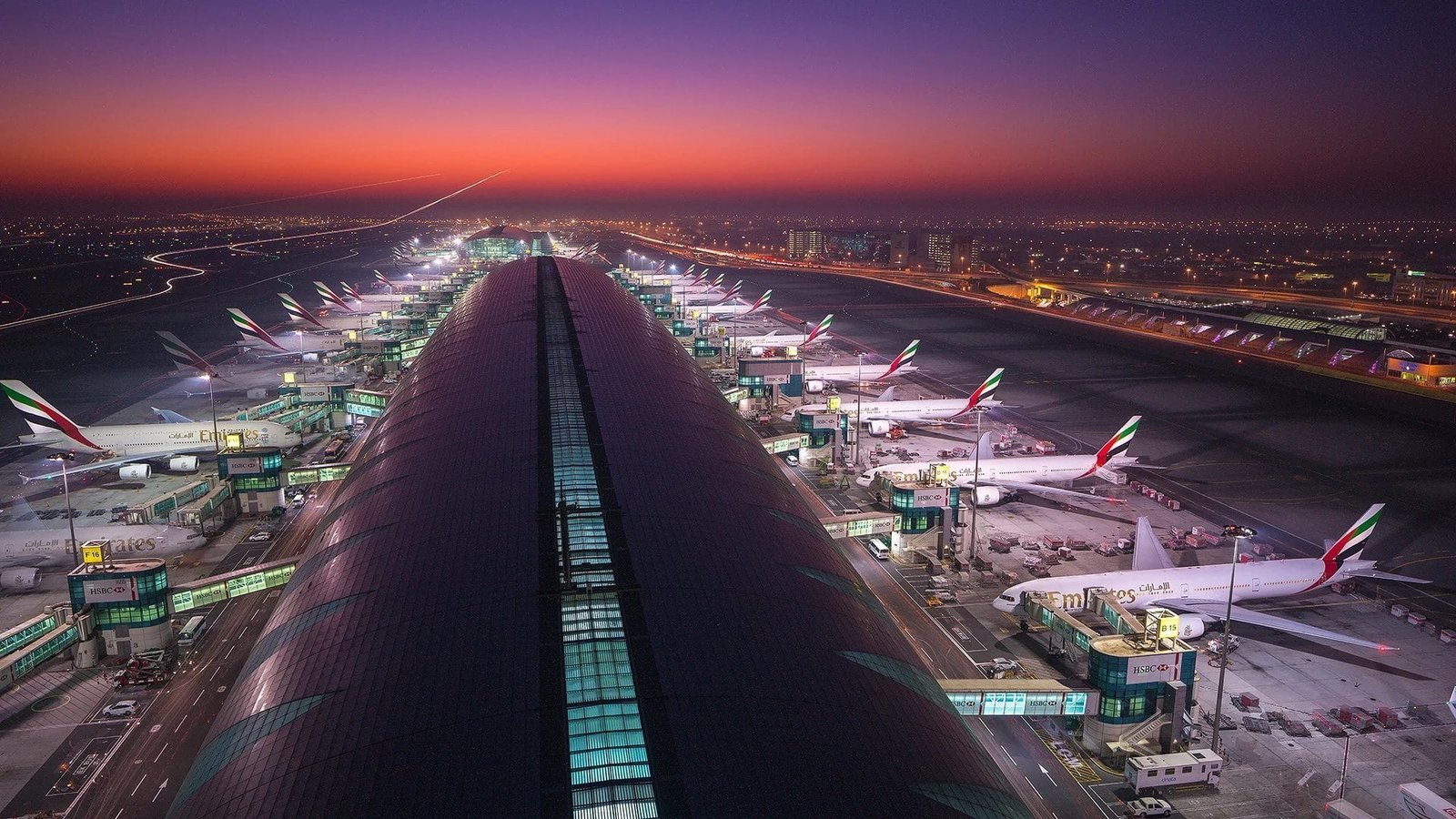 Night view of Dubai International Airport showing terminal buildings, aircraft stands, taxiways and coordinated ground operations.